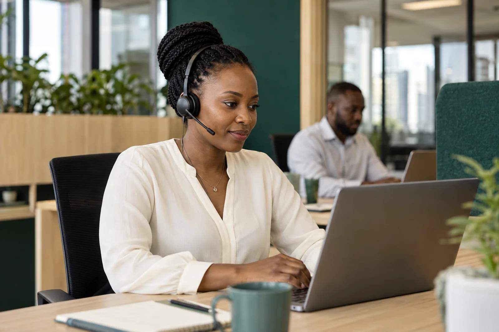 An African customer operations specialist using a headset and laptop